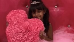 Young girl wearing a tiara holding up a fluffy pink pillow