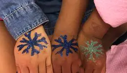 Fisted hand of three girls with glittery snowflake art