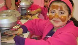 Young girl in a pink robe and headband with a honey mask on her face